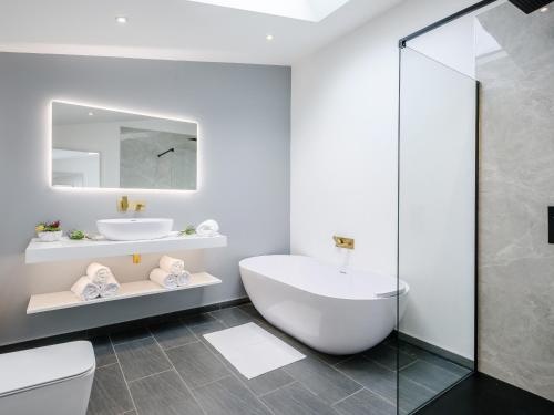 a white bathroom with a tub and a sink at Marshall Cottage in Santon