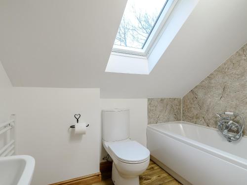 a bathroom with a toilet and a bath tub and a window at Farriers Lodge in Burshill