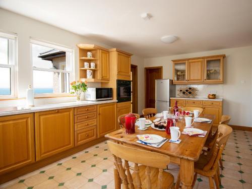 uma cozinha com uma mesa de madeira com cadeiras em Cairn-o-mhor em Lendalfoot