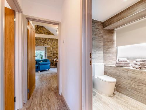 a bathroom with a toilet and a blue couch at Shawdon Hill Coach House in Whitby