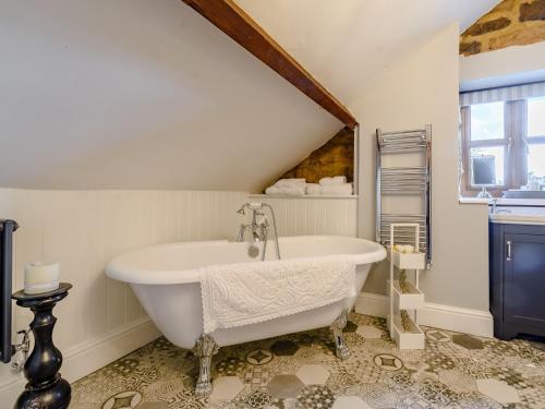 - une salle de bains mansardée pourvue d'une baignoire blanche dans l'établissement The Old Barn, à Cloughton