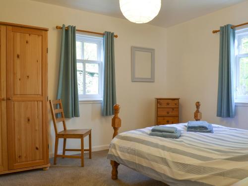 a bedroom with a bed and a chair and windows at Eagles Gate Lodge in Banff