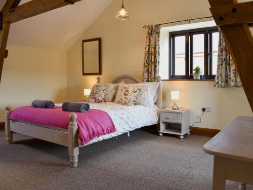 1 dormitorio con 1 cama con manta rosa en Bucknole Farm - The Old Shippon en Northleigh