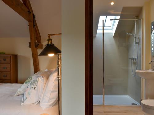 a bedroom with a shower and a bed with a lamp at Bucknole Farm - The Old Shippon in Northleigh
