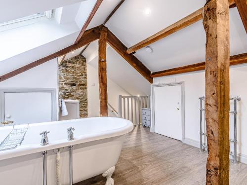 a bathroom with a large white bath tub and wooden beams at Ghyll View in Gunnerside