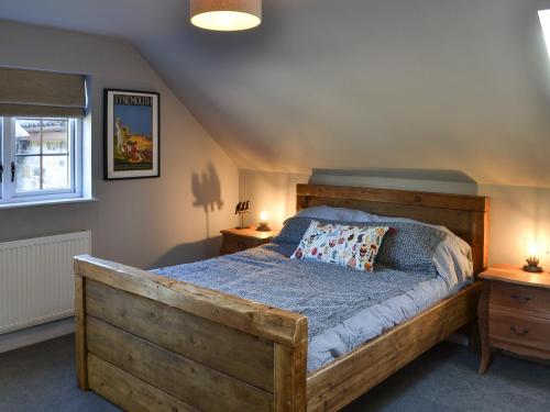 1 dormitorio con 1 cama de madera y 2 mesitas de noche en Honeypot Cottage en Rothbury