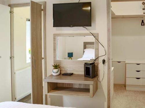 ein Schlafzimmer mit einem Bett und einem TV an der Wand in der Unterkunft Ocean Glade - Uk32963 in Corton
