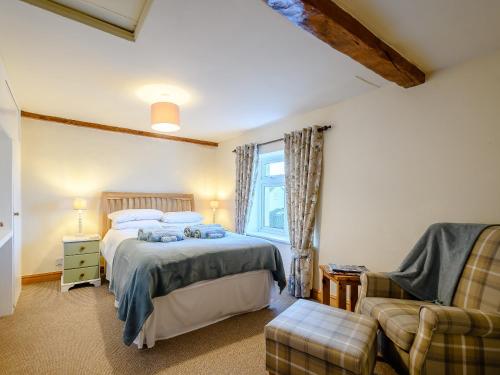 a bedroom with a bed and a chair and a window at Curlew Cottage in Mawbray
