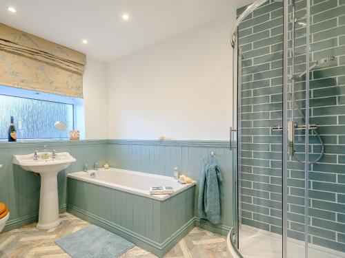 a bathroom with a tub and a sink and a shower at Curlew Cottage in Mawbray
