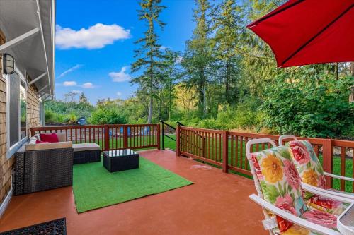 a patio with a red umbrella and chairs on a deck at Relajate y recargate de buena vibra en nuestras cabanas de Camano Island in Camano