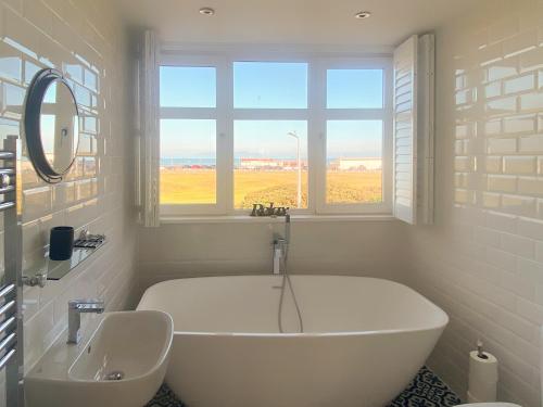 uma banheira branca na casa de banho com uma janela em Helena em Prestwick