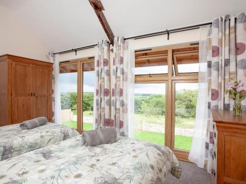 a bedroom with two beds and a large window at Orchard Barn in South Tawton