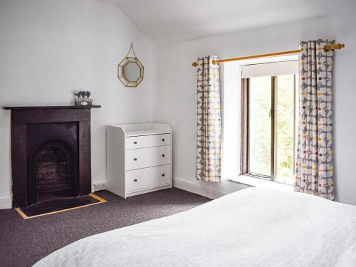 a bedroom with a bed and a fireplace and a window at Caer Elen in Dolwyddelan