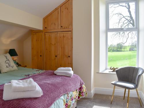 a bedroom with a bed and a chair and a window at Tormire Laithe in Bell Busk