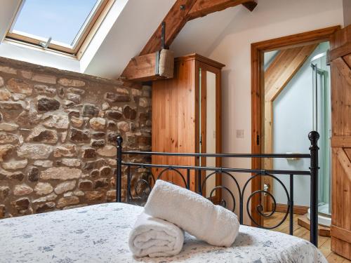 um quarto com uma cama e uma parede de pedra em Fox Cover Cottage em Great Edston