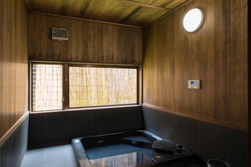 a bathroom with a window and a tub in a room at Busuitei in Hida