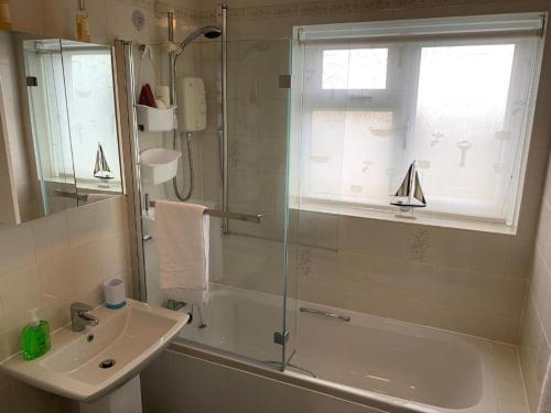 La salle de bains est pourvue d'une douche, d'un lavabo et d'une baignoire. dans l'établissement Paignton View, à Paignton