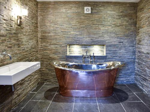 uma grande banheira de cobre numa casa de banho com um lavatório e uma banheira tubermottermott em Ivy House em Dockray