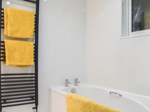 a bathroom with a white tub and yellow towels at Ty Isaf in Barmouth