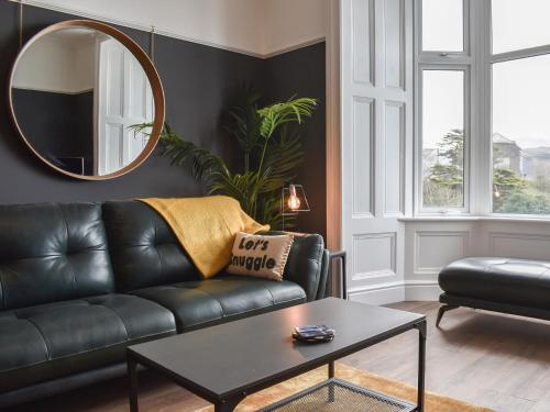 a living room with a black leather couch and a mirror at Ty Isaf in Barmouth
