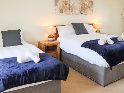 1 dormitorio con 2 camas con sábanas azules y blancas en Llwyn Ysgaw en Cemaes Bay