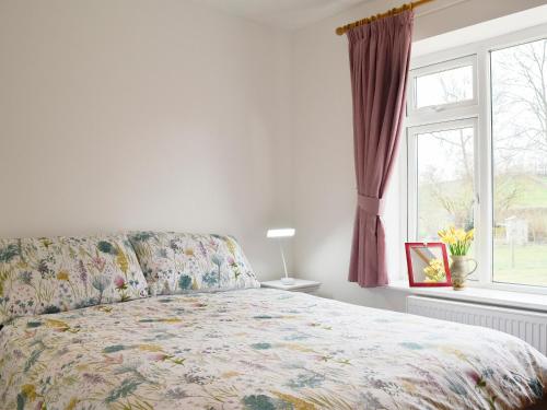 a bedroom with a bed and a window at Forest View in Llanfihangel Rhydithon