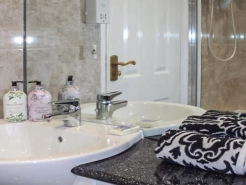 a bathroom with a white sink and a mirror at Hollyhocks Bungalow - Uk39617 in Welcombe