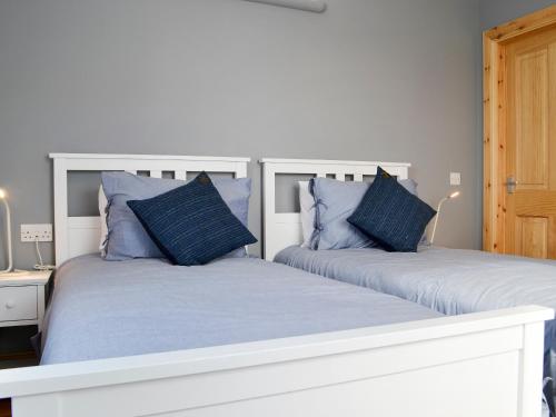 2 bedden met blauwe kussens in een slaapkamer bij Healair in Garrabost