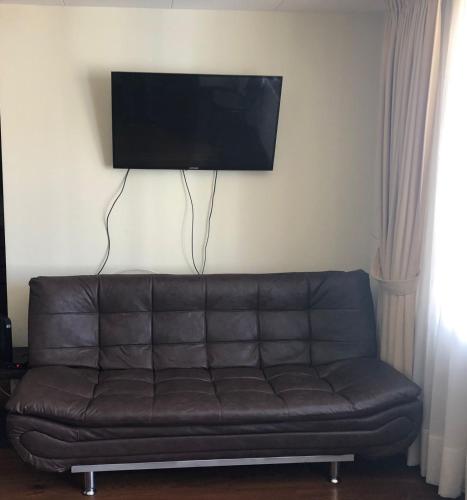 - un canapé en cuir brun dans le salon avec une télévision à écran plat dans l'établissement Familiar y acogedor, à La Paz