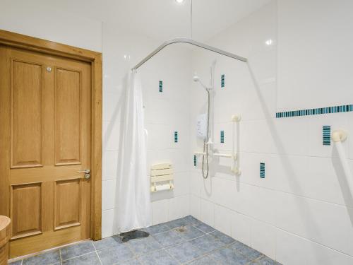 baño con ducha y puerta de madera en Riof Ocean Cottage - Uk7125, en Valtos