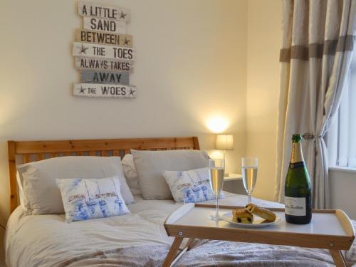a bed with a table with two glasses and a bottle of wine at Hafod Y Bryn in Benllech