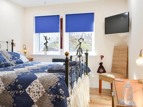 a bedroom with a bed with blue curtains and a tv at 4 Dolphins in Connel