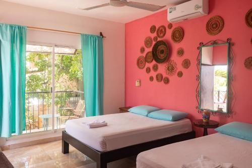 two beds in a room with pink walls and a window at Hostal Tunich Naj & Hotel in Valladolid