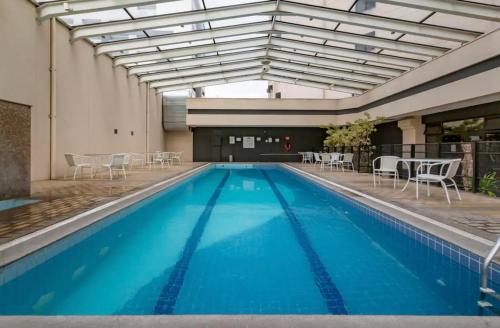 a large swimming pool with chairs and tables in a building at Apartamento Congonhas 2207 torre Suites in Sao Paulo