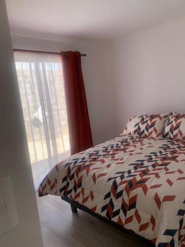 a bedroom with a bed with a comforter and a window at Loreto y Rodillo in Caldera