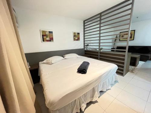 Un dormitorio con una cama con un sombrero negro. en Flat moderno com piscina e academia, en Itaboraí
