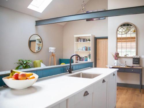 a kitchen with a sink and a bowl of fruit on a counter at Stabl in Cross Inn