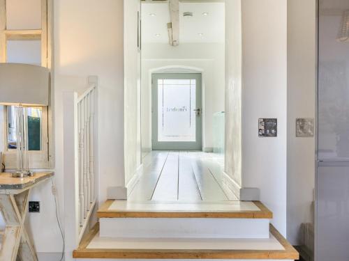 korytarz z białymi ścianami, drewnianą podłogą i oknem w obiekcie The Cow Shed w mieście Buckland St Mary