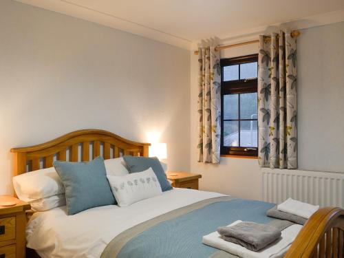 1 dormitorio con 1 cama con almohadas azules y blancas en Hoot House, en Abergynolwyn