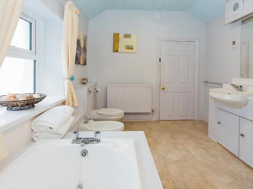 a white bathroom with a sink and a toilet at Eventide in Pembroke Dock