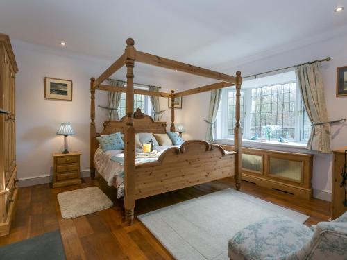 1 dormitorio con cama de madera con dosel y ventana en Twisly North Lodge, en Catsfield