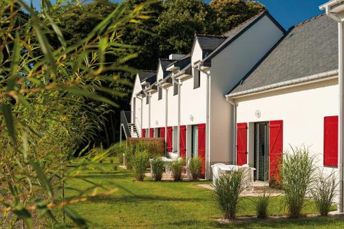 a row of white buildings with red doors at Lagrange Vacances Domaine de Val Queven in Quéven