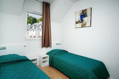 a bedroom with two beds and a window at Lagrange Vacances Domaine de Val Queven in Quéven