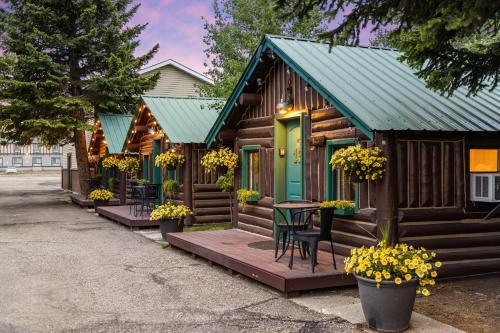 a log cabin with a green door and a table and chairs at The Bucking Moose in West Yellowstone