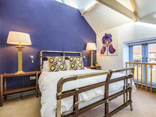 a bedroom with a bed and a blue wall at The Cider Barn in Buckland St Mary