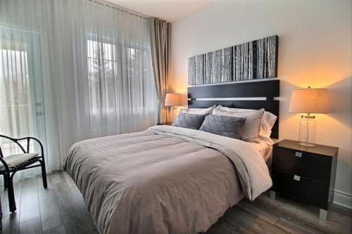1 dormitorio con 1 cama grande y 1 silla en LeChamplain #206 CITQ#248275, en Bromont