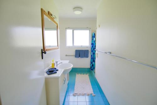 uma casa de banho com um lavatório e um espelho em Cadel’s Cottage em Burnt Pine