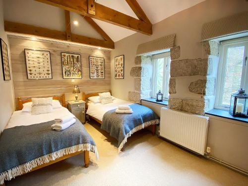 a bedroom with two beds and two windows at Swallows Barn in Crowan