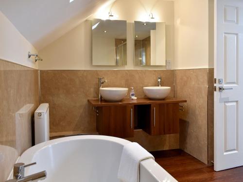 a bathroom with two sinks and a bath tub at Bay View in Carlyon Bay