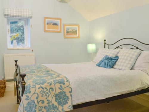 a bedroom with a bed with a blue and white blanket at The Granary in Dunvant